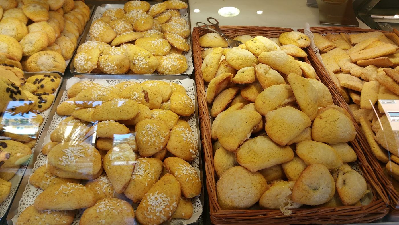 Vassoi di biscotti bolognesi su carta pizzo e cesti di vimini nel banco del forno